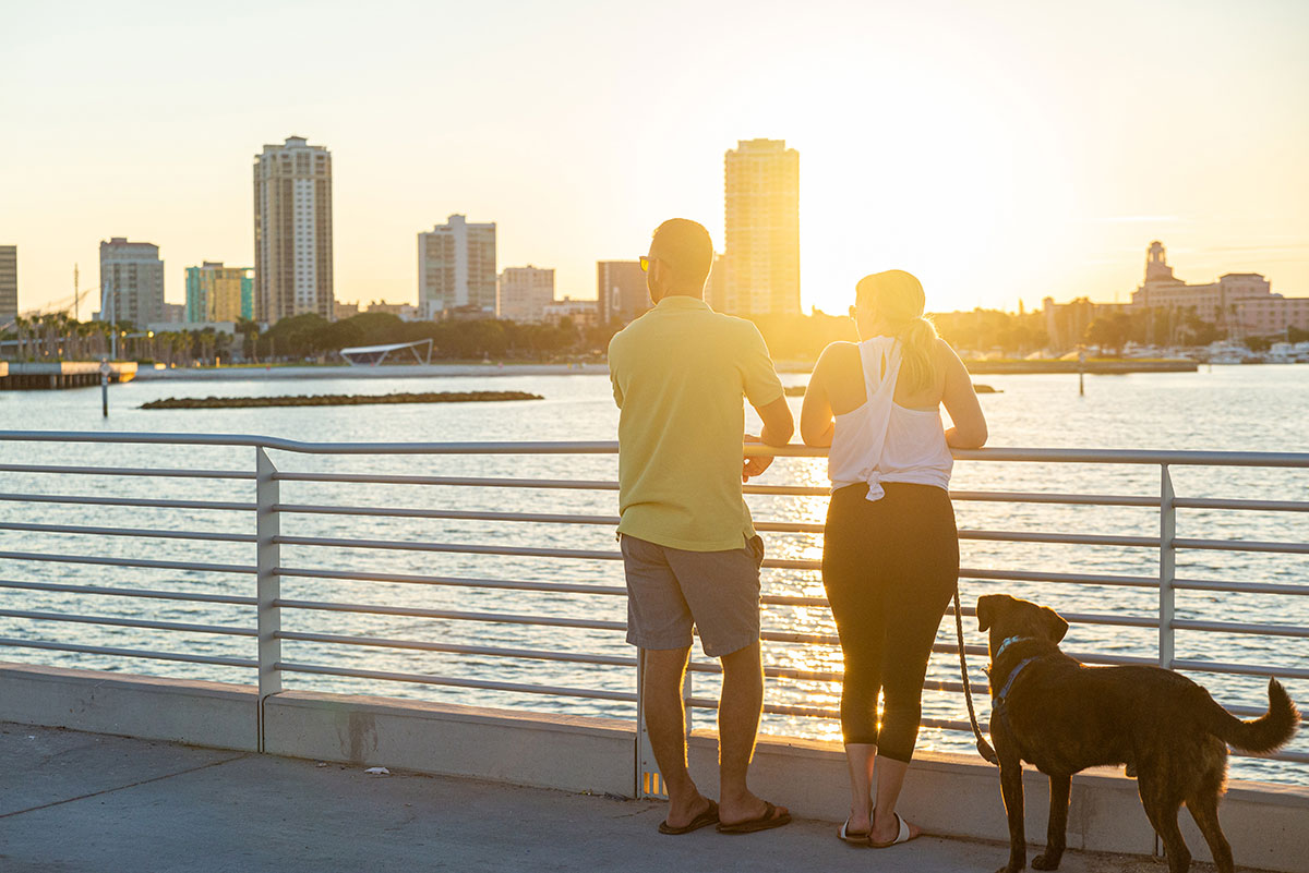 couple with dog overlooking bay at sunset