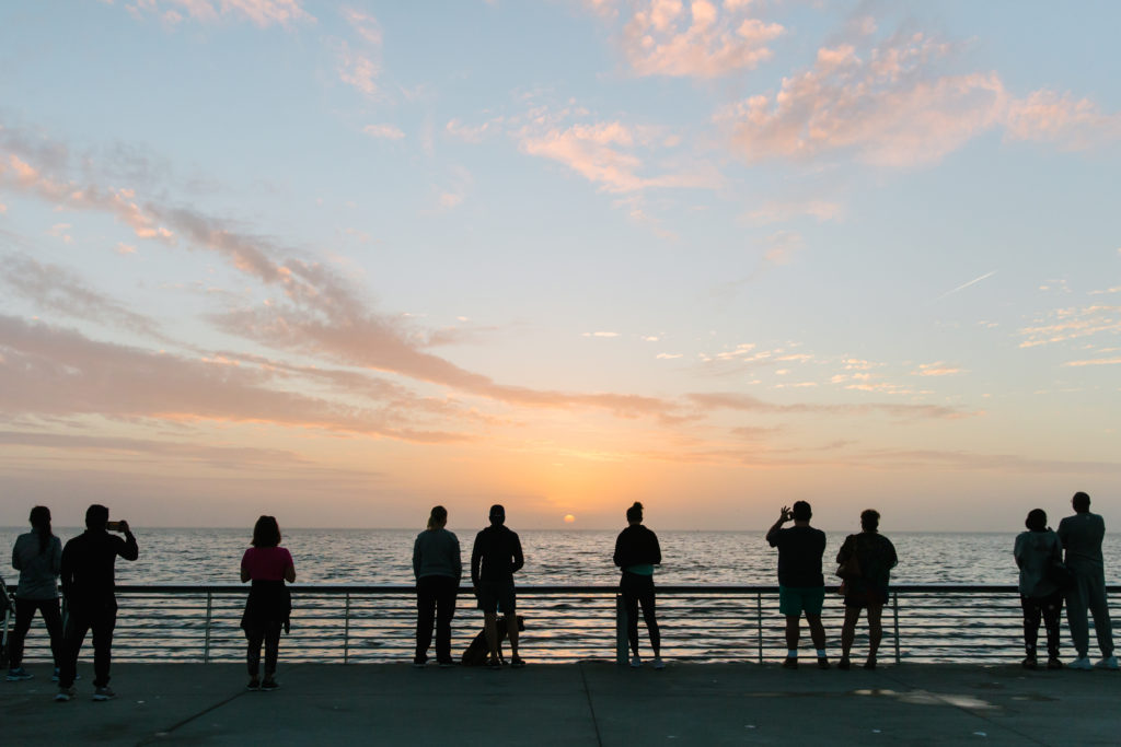 people watching sunrise off pier